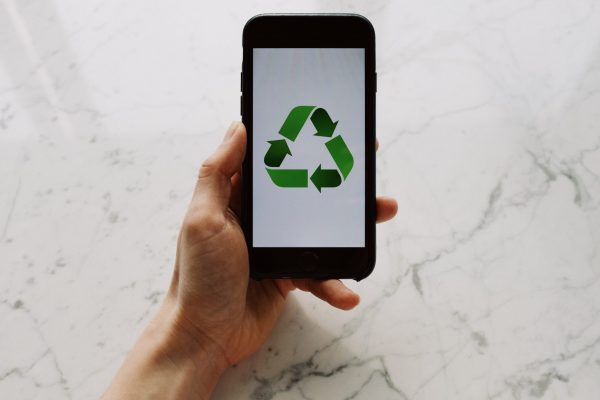 Important-Steps-to-Take-Before-You-Recycle-image-scaled.jpg From above view of faceless person holding mobile phone with white screen and green recycle logo above marble surface
