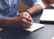 Free Person Writing on Paper Using Yellow and Black Pen Stock Photo