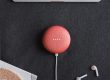 flat lay photography of coral Google Home Mini on black surface beside Apple AirPods