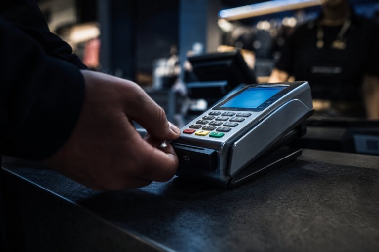 Hand pressing buttons on an EFTPOS terminal at a shop counter
